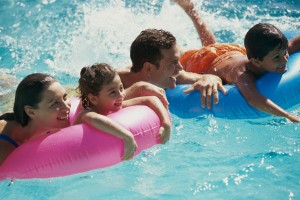 Family relaxing on inflatable rafts in a swimming pool